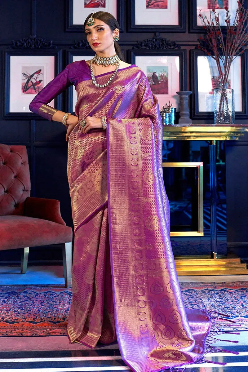 Woman in a traditional saree standing in an elegant room with decor elements.