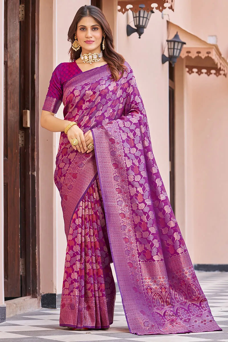 Woman wearing a purple and pink saree with a traditional setting