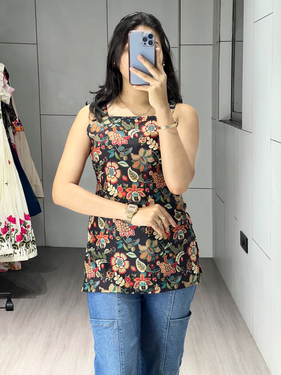 Woman wearing a floral top and jeans in a room with a mirror.