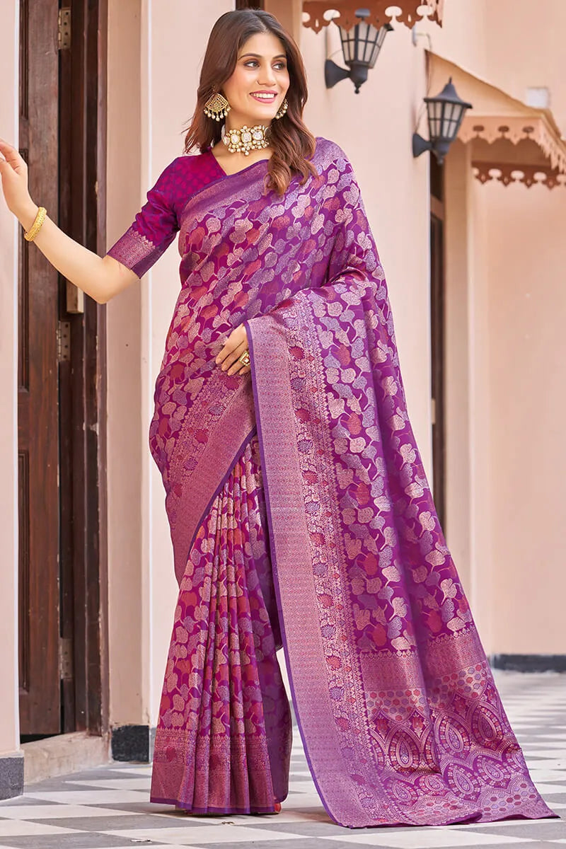 Woman wearing a purple saree with a floral pattern in an outdoor setting.