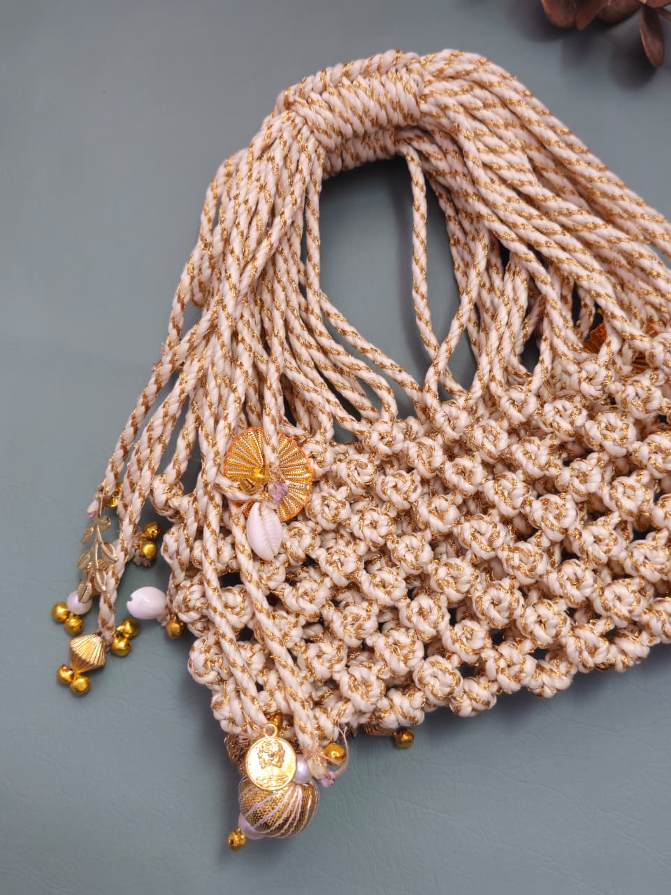 Beige woven bag with decorative elements on a gray background