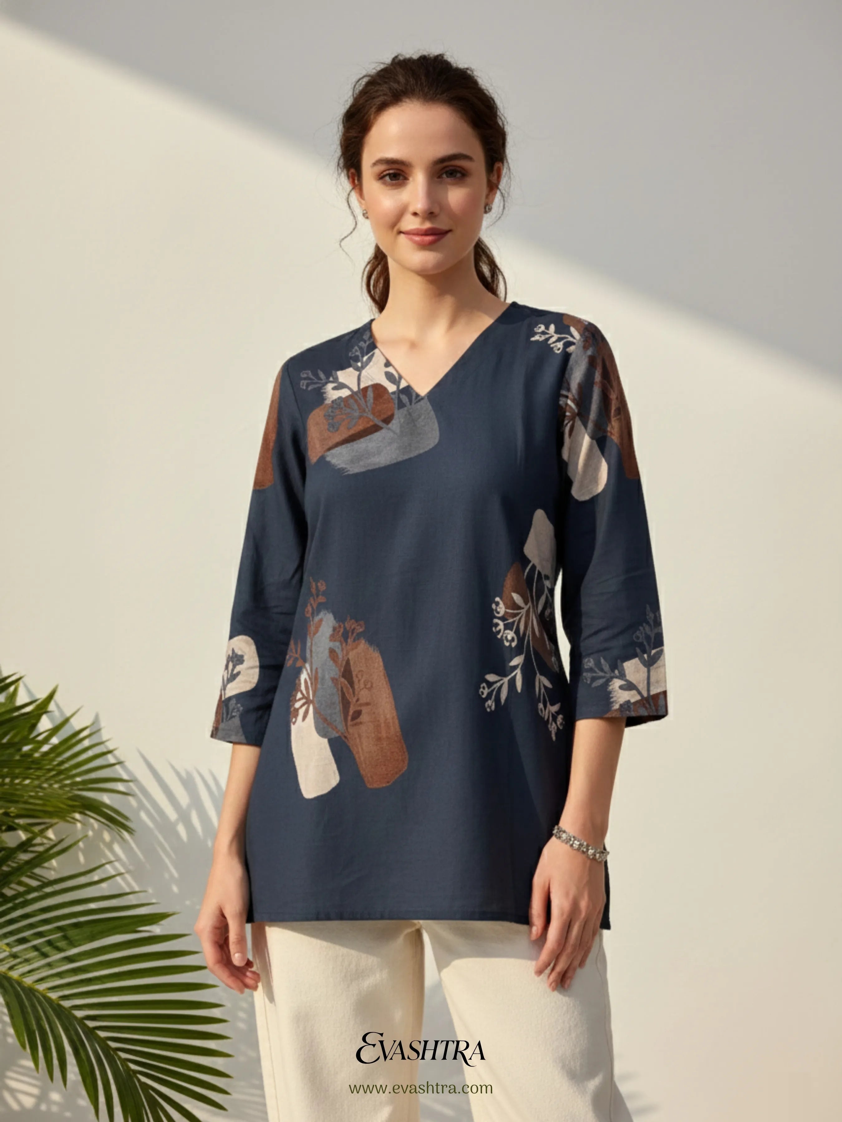 Woman wearing a navy blue floral blouse with a white background and palm leaves.