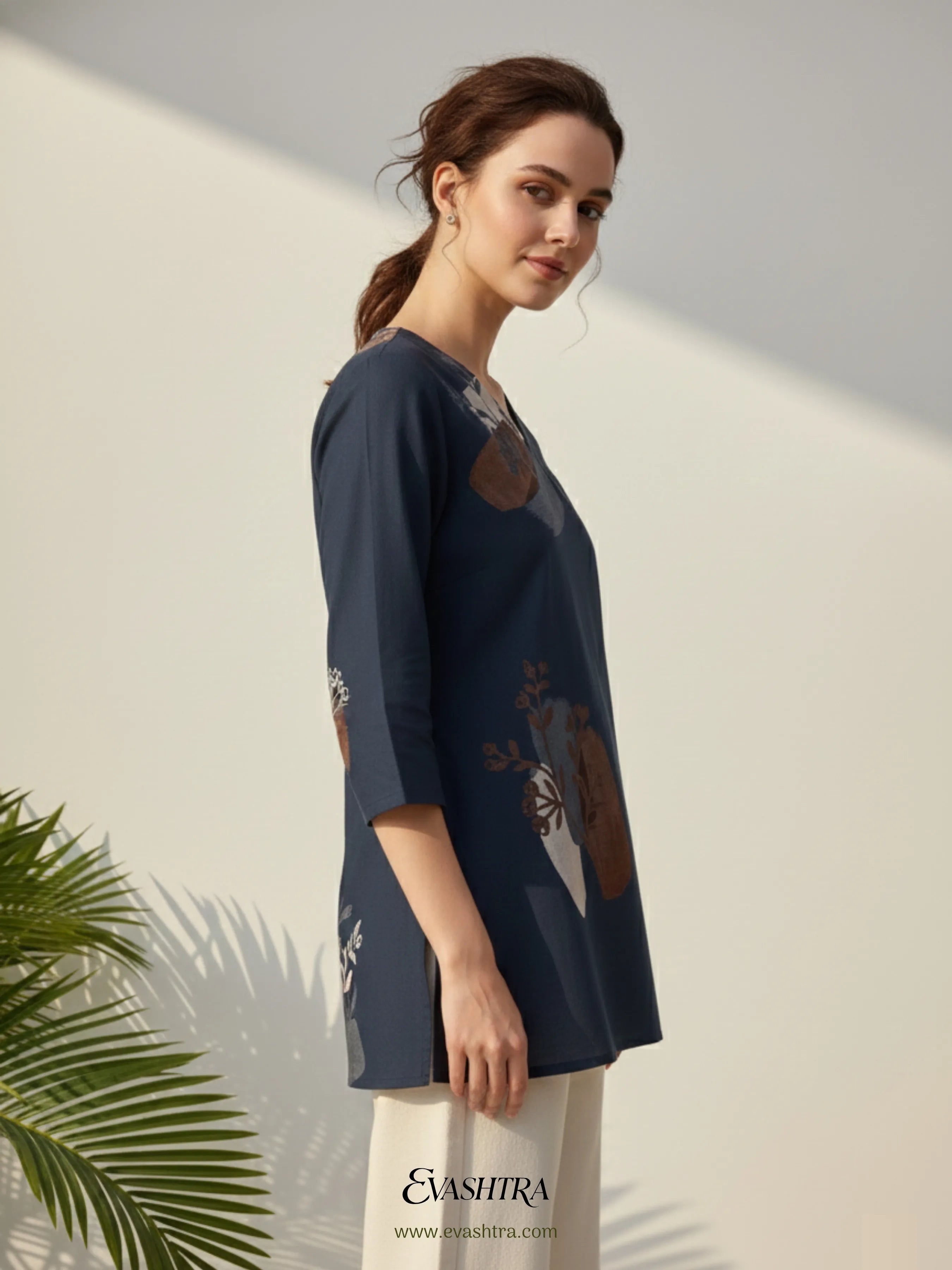 Woman wearing a navy blue embroidered top with a white background and 'Evashira' branding.