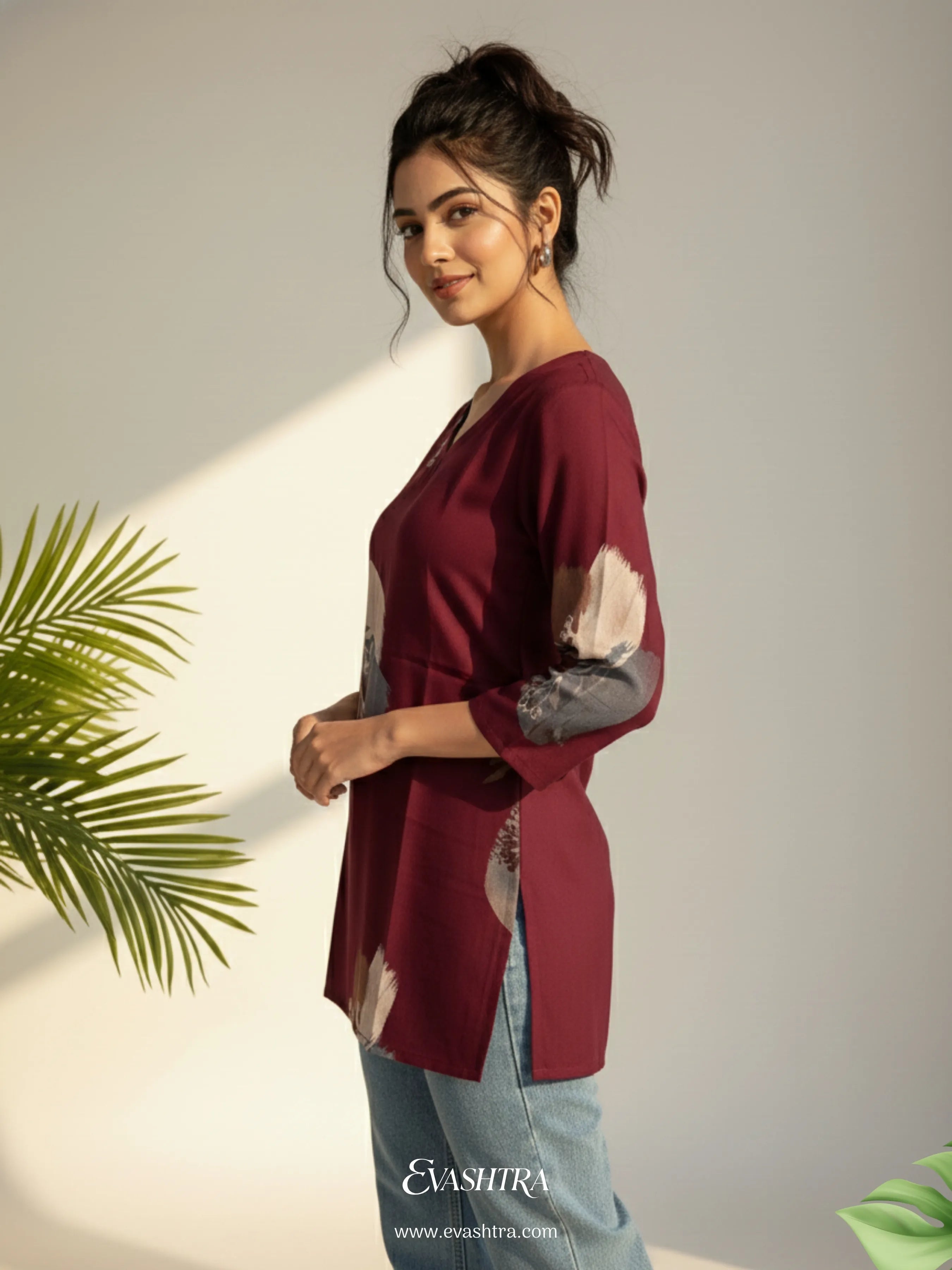 Woman wearing a burgundy top with a brand logo in the corner