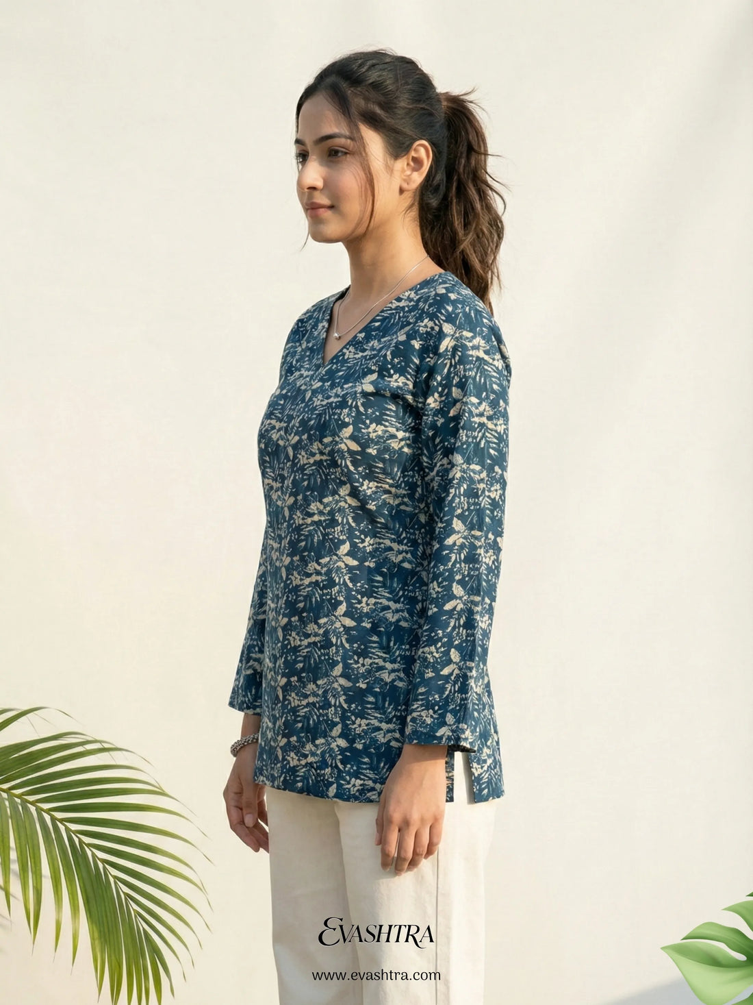 Woman wearing a blue floral blouse with a white background and green leaves.