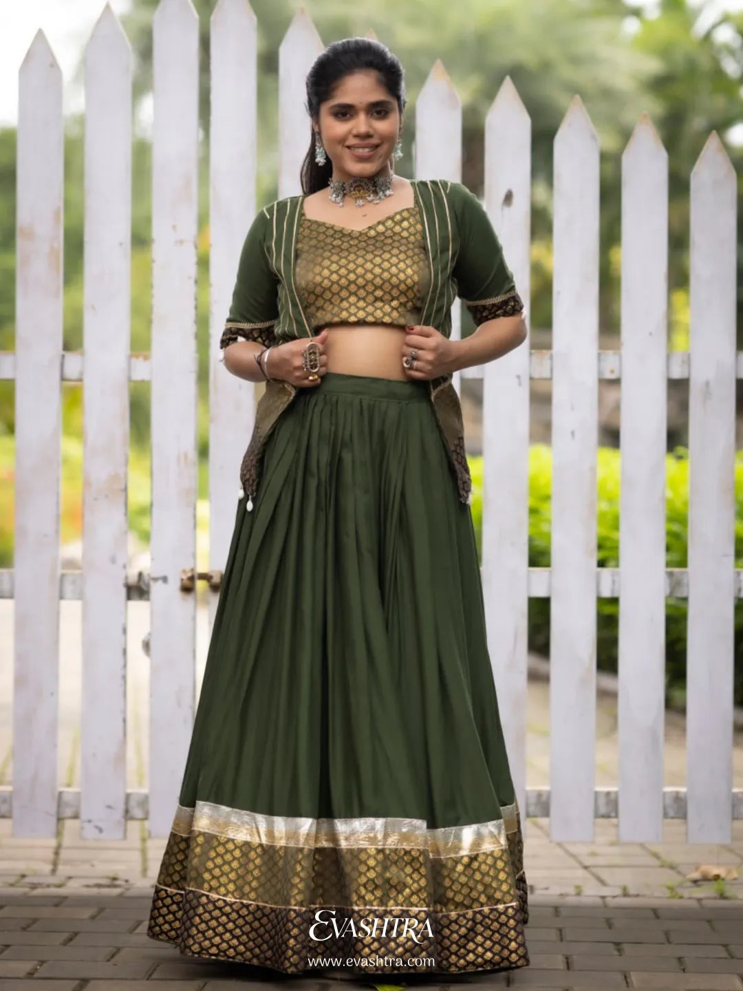 Woman wearing a green traditional outfit with a white picket fence 1