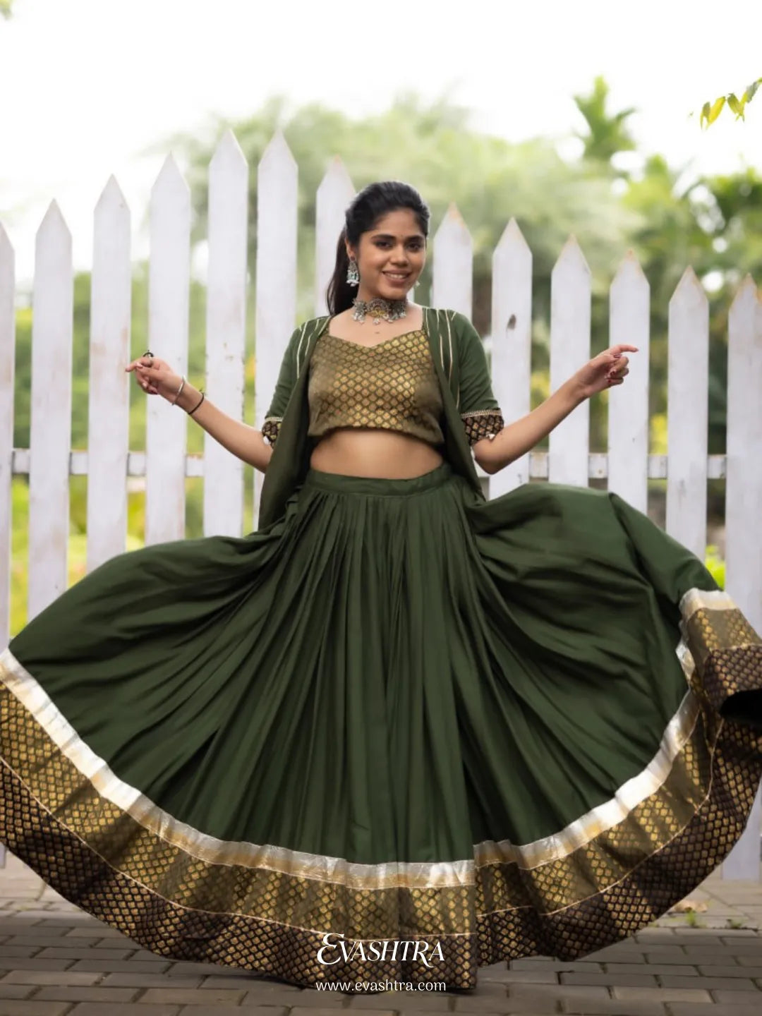 Woman wearing a green traditional outfit with a white picket fence 2