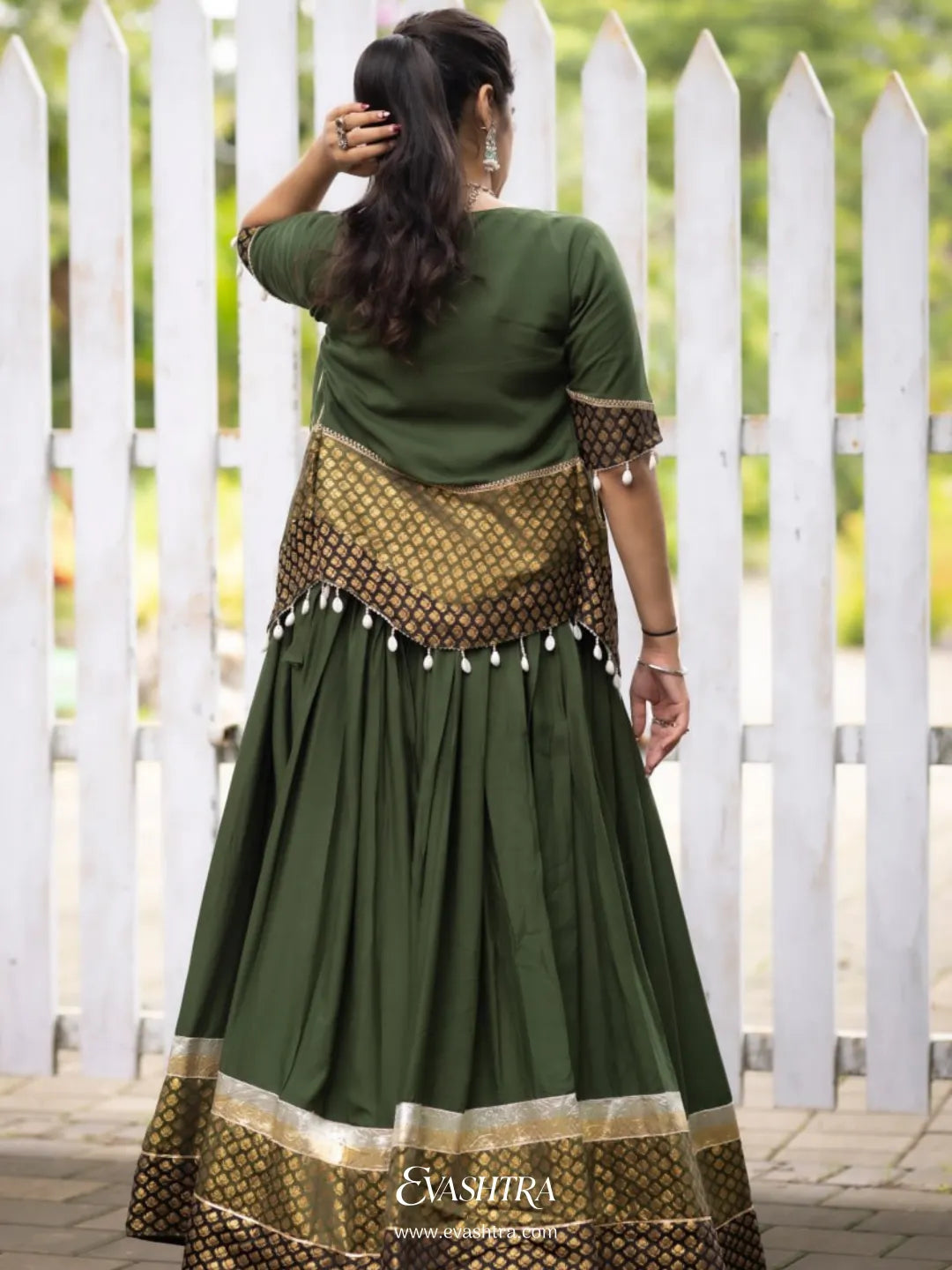Woman wearing a green traditional outfit with a white picket fence 3
