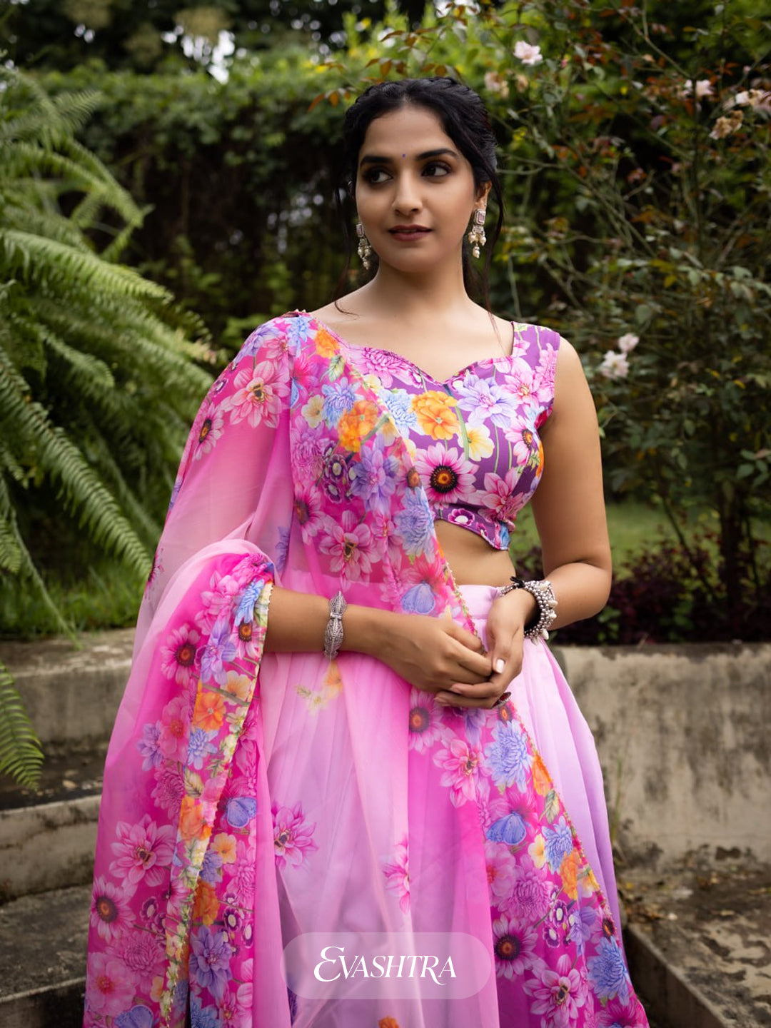 Woman wearing a pink floral traditional outfit with 'EvaShira' branding.