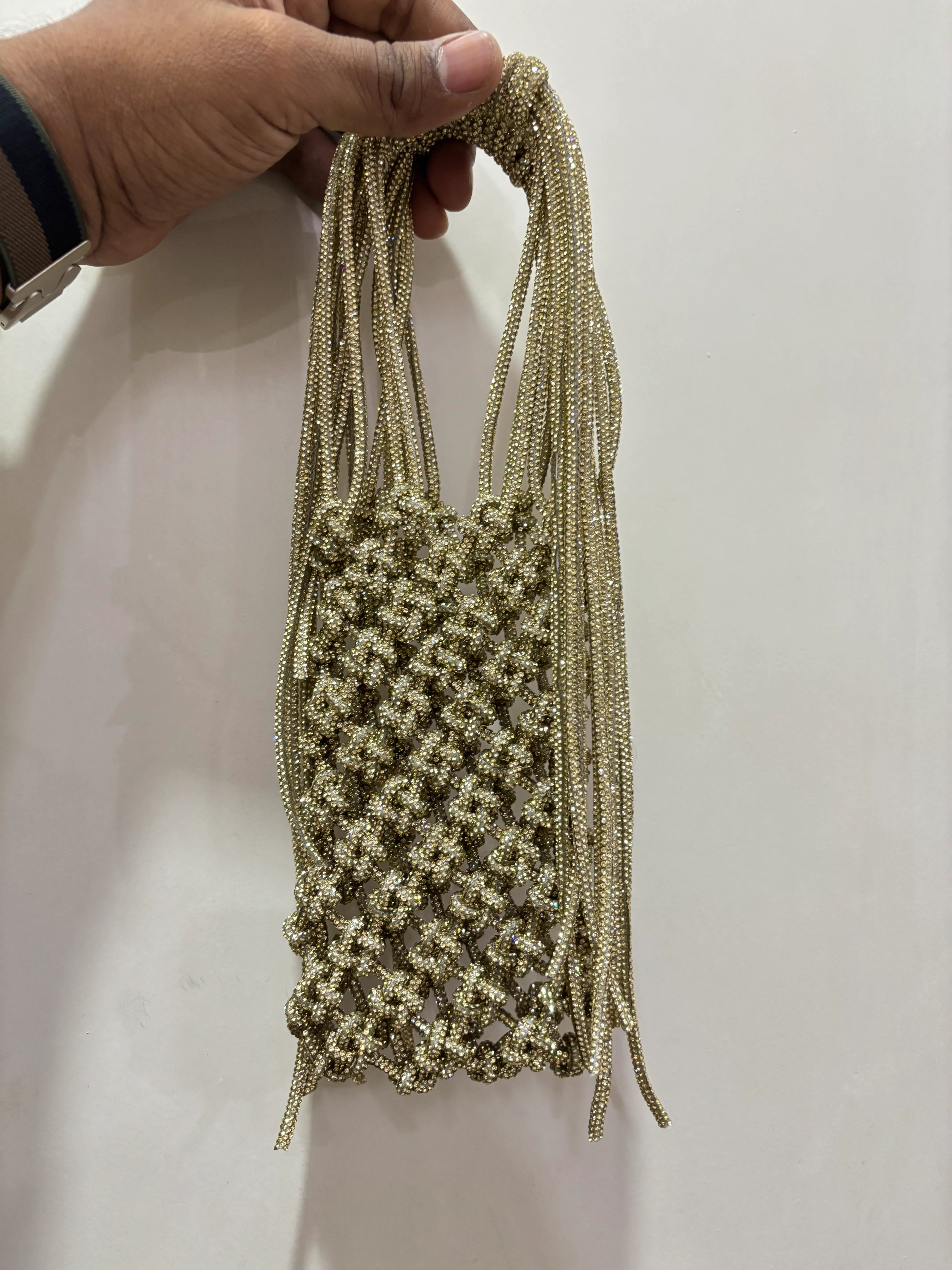 Hand holding a braided beige cord against a plain background