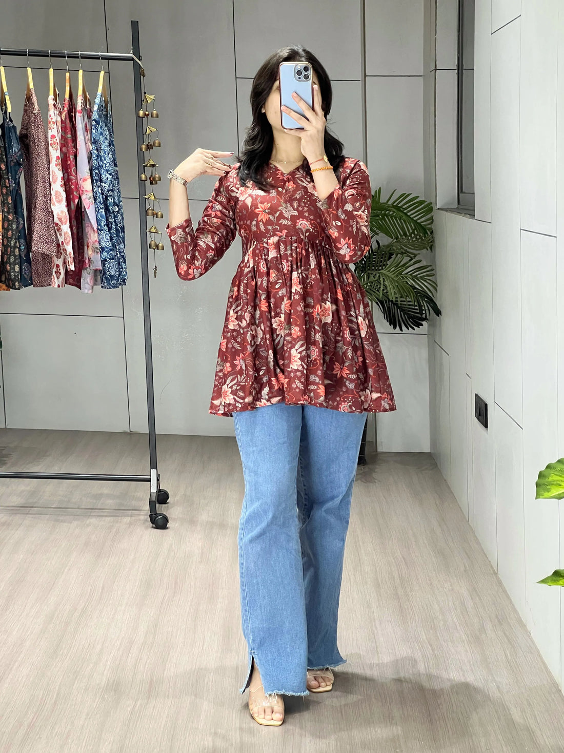 Person wearing a floral top and blue jeans in a store setting.
