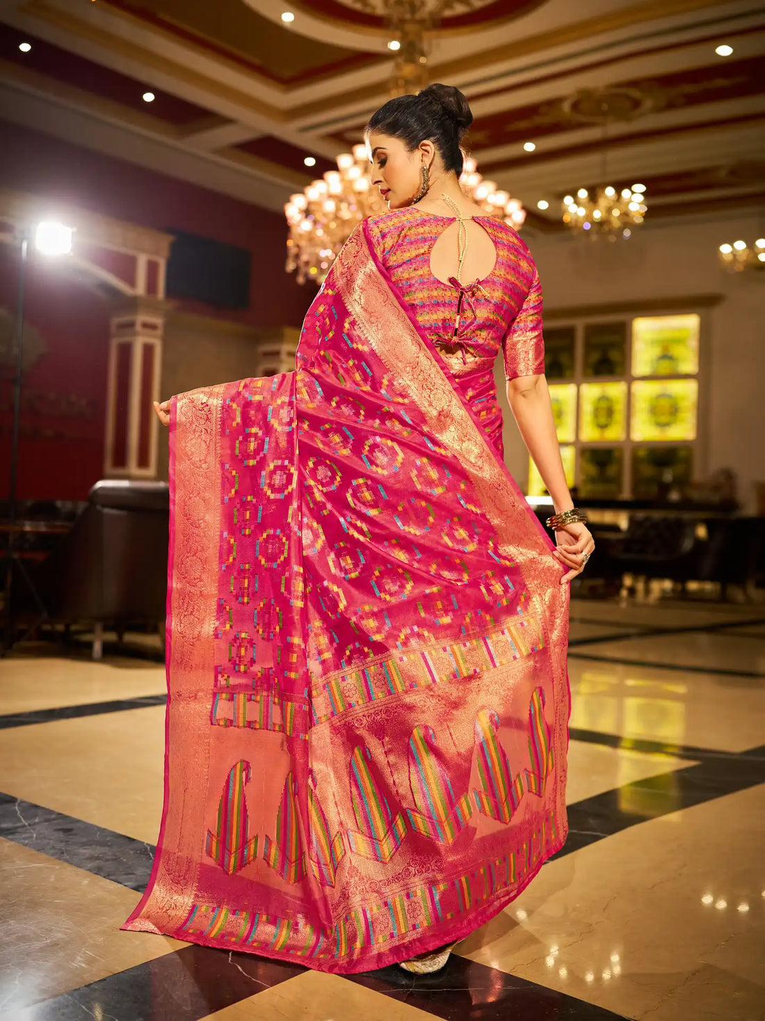 Woman in a pink saree with a patterned design in an indoor setting