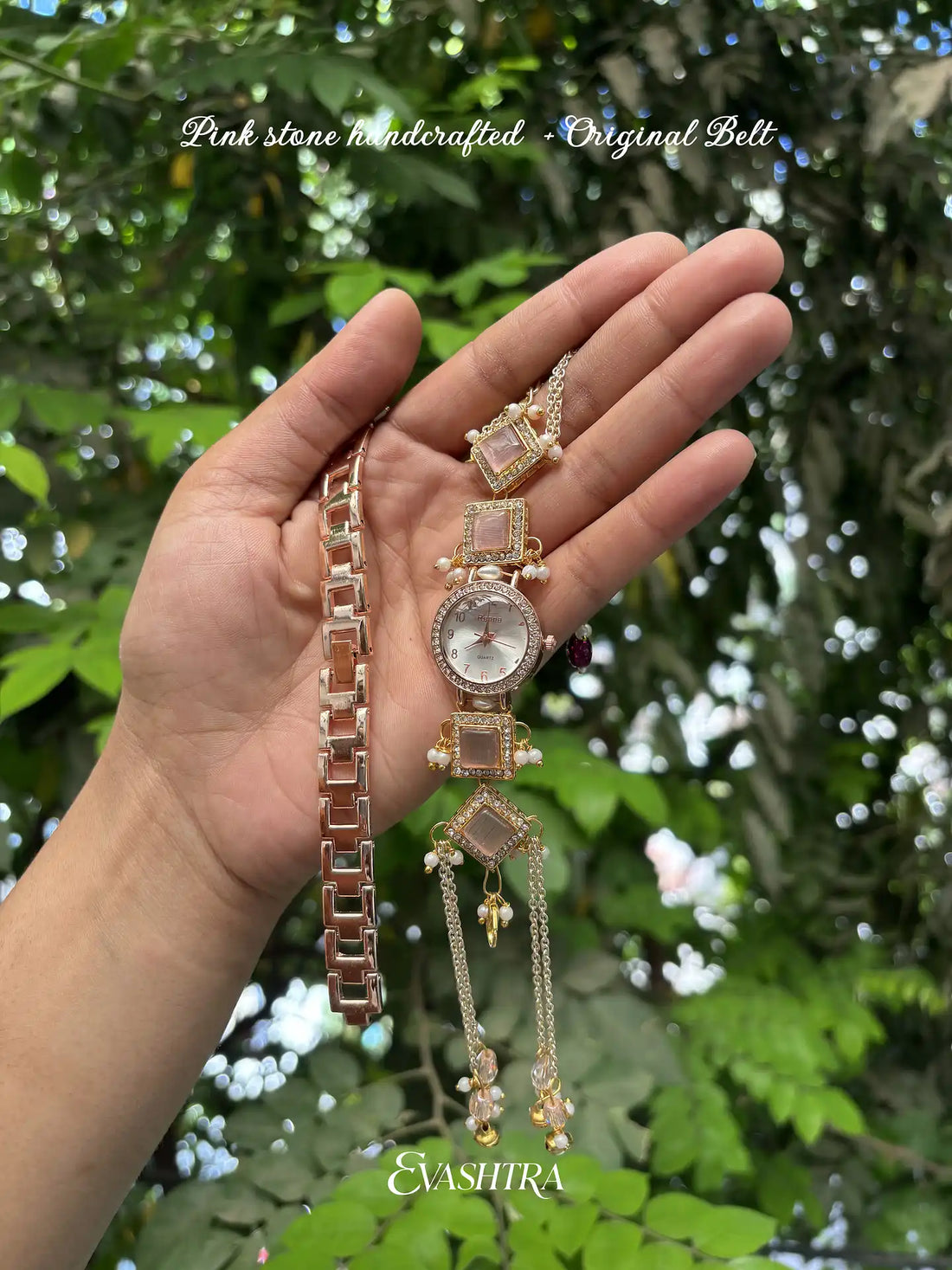 Hand holding a decorative watch and bracelet with a blurred green leafy background