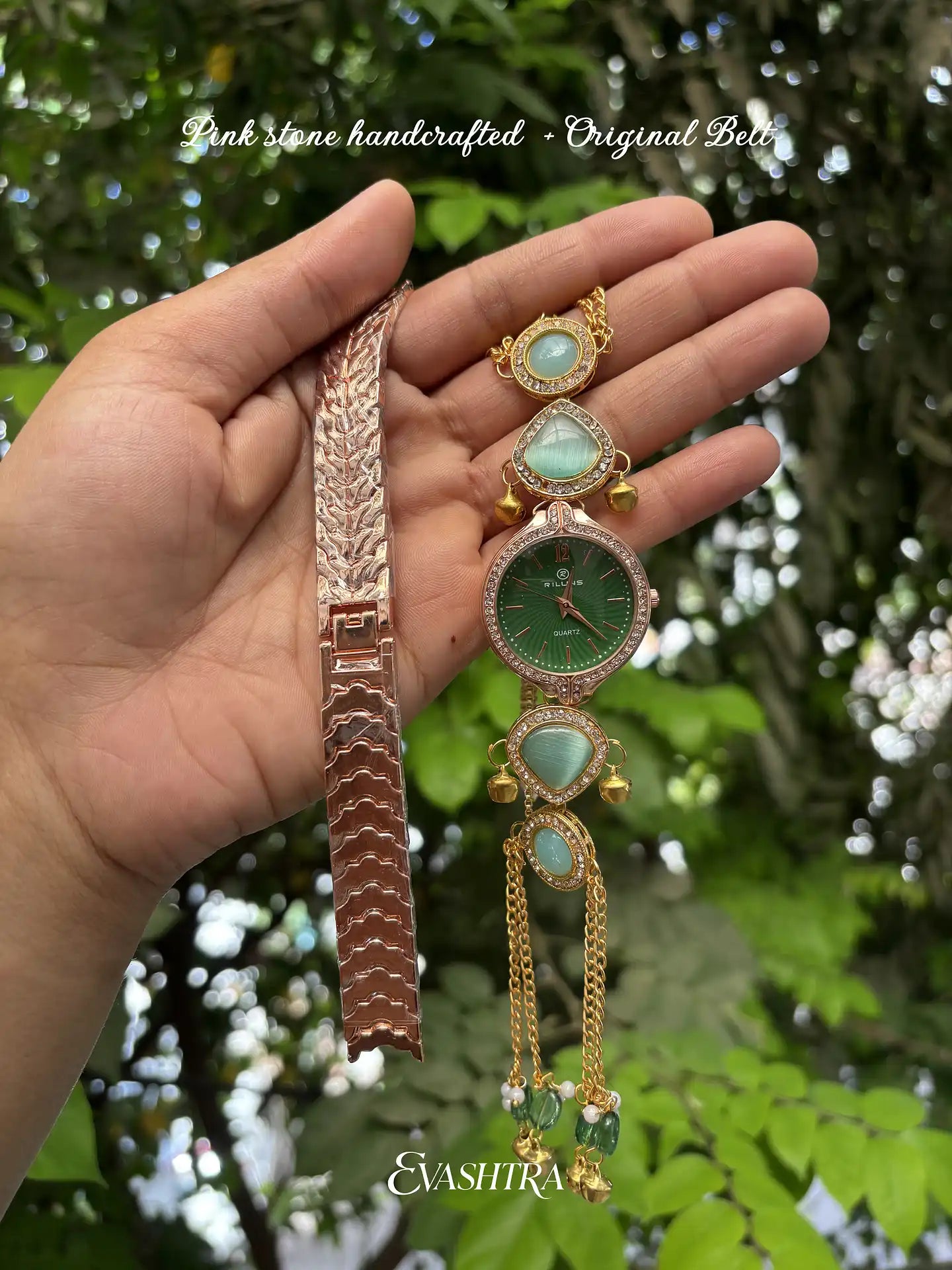 Hand holding a decorative bracelet with green gemstones against a blurred green leafy background