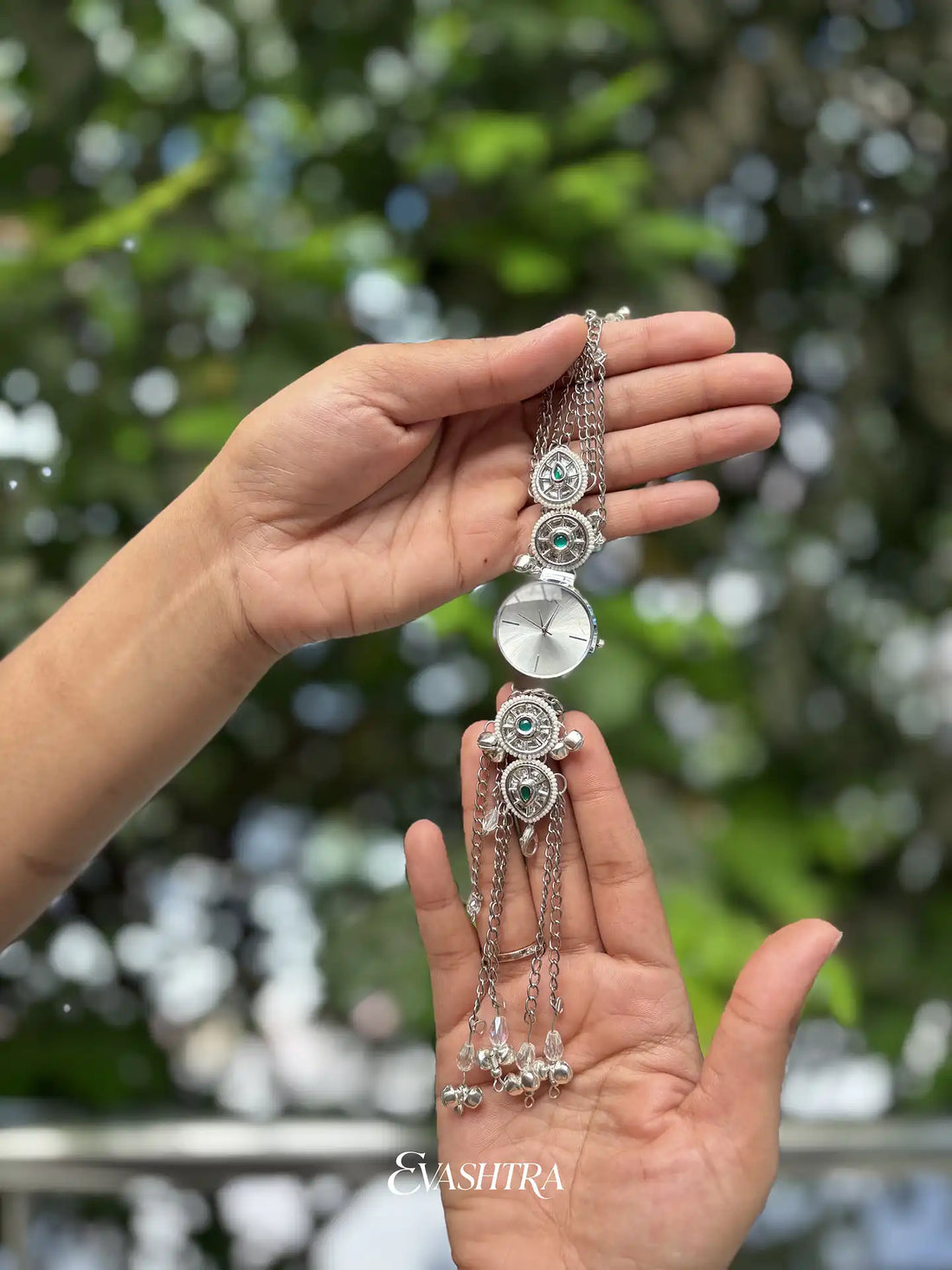 Hand holding a decorative hair accessory with greenery in the background