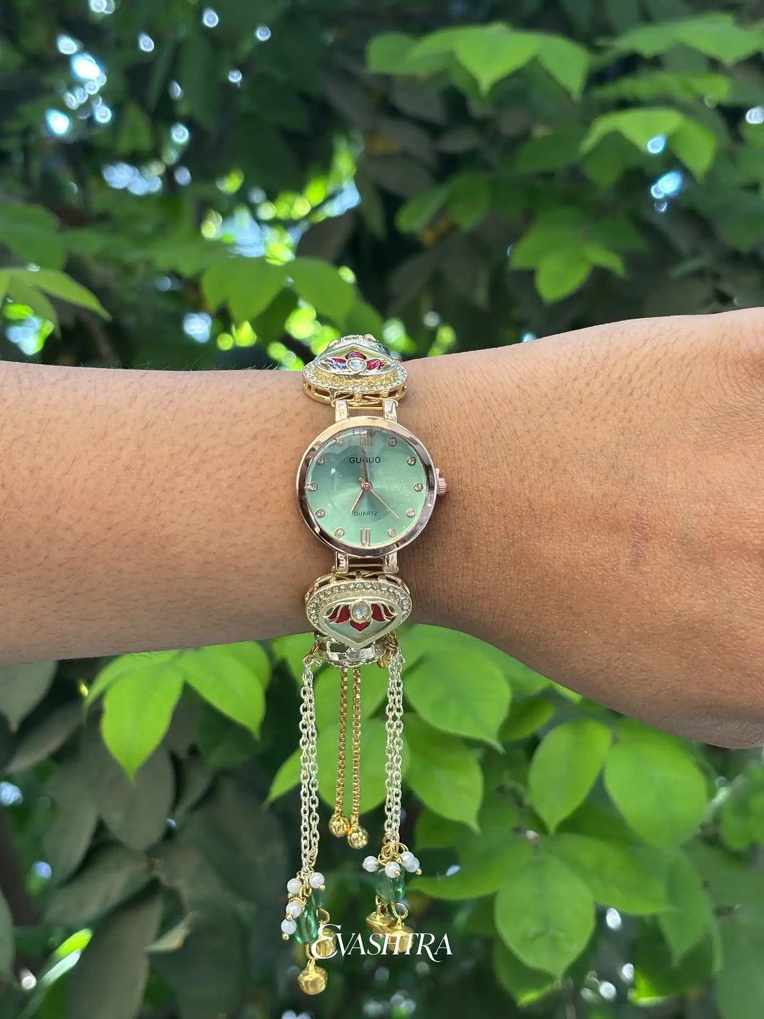 Decorative watch on a wrist with a green leafy background