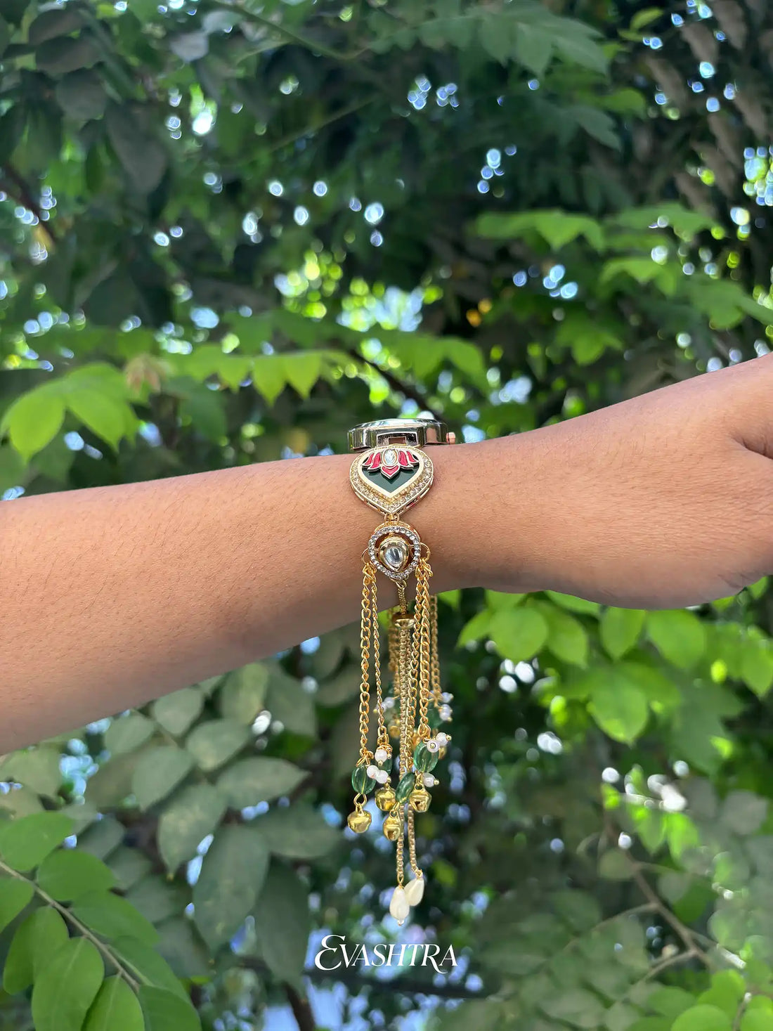 Bracelet with decorative elements on a wrist against a green leafy background