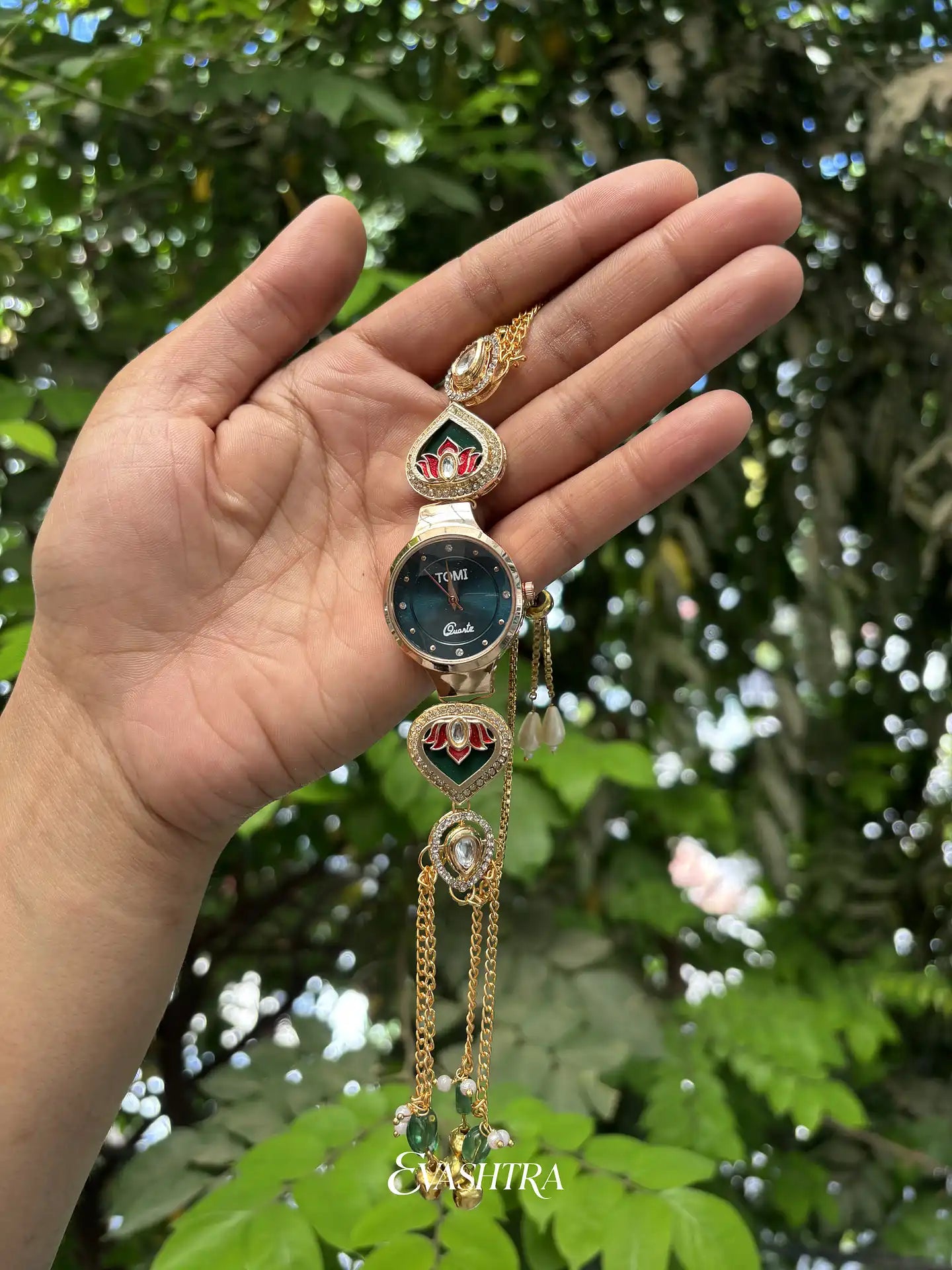 Decorative watch held in a hand with a green leafy background