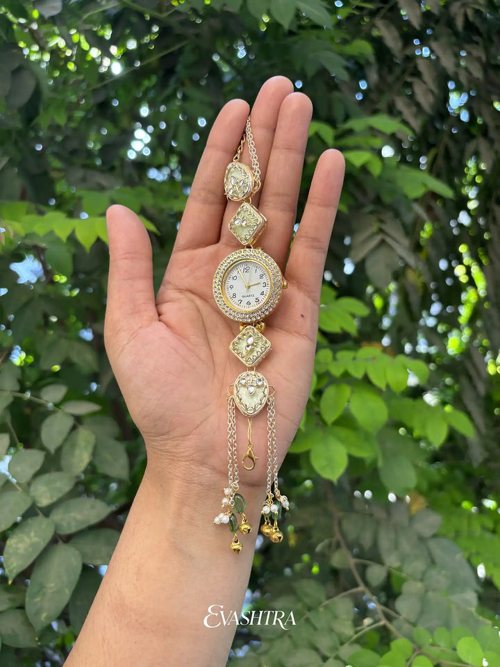Gold and diamond-studded watch held in a hand with a green leafy background